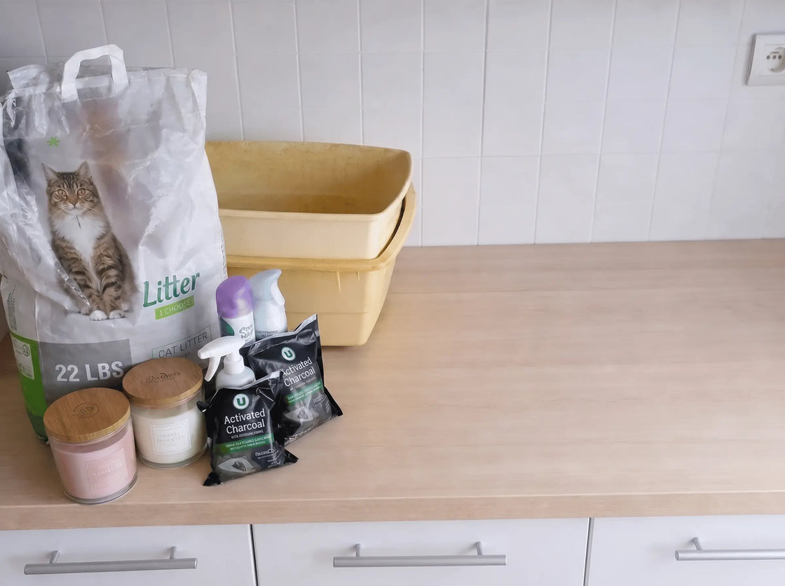 A countertop cluttered with anti-smell weapons: bag of litter, candles, sprays, charcoal sachets