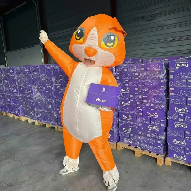The Pacha mascot with a pack of litter, in front of pallets of donations for shelters
